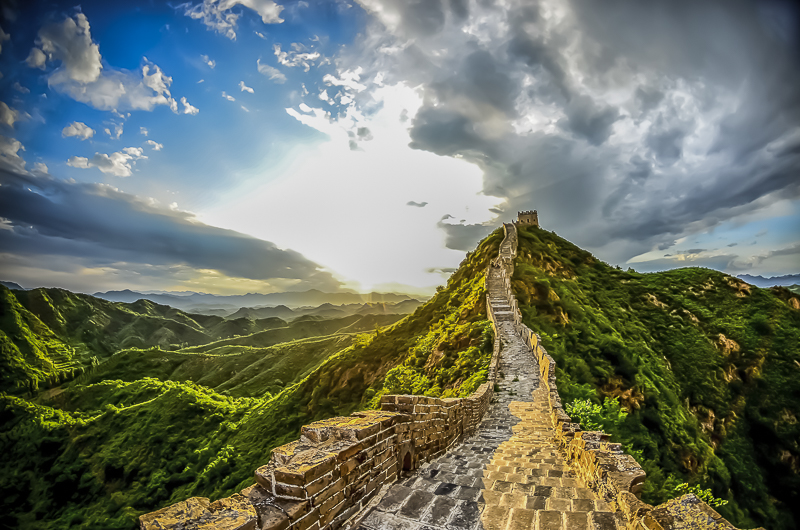 Ancient stone wall winding along the crest of verdant hills under a dramatic sky.