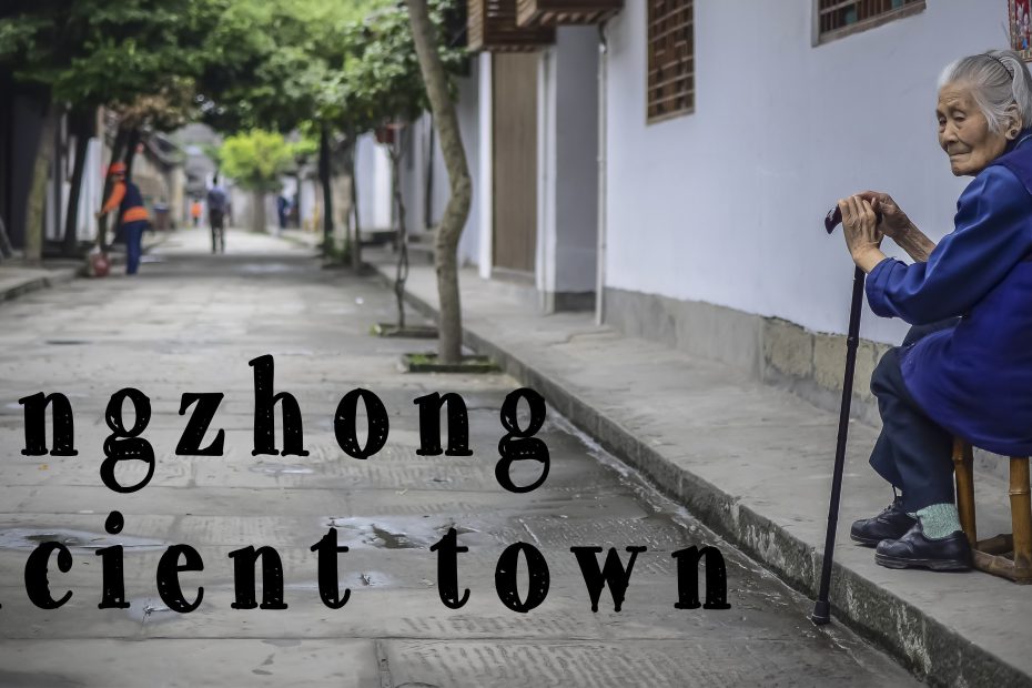 An elderly woman sits with a cane on the steps of a building in Langzhong Ancient Town, contemplating as passersby walk along the traditional street, capturing the essence of a travel blog.
