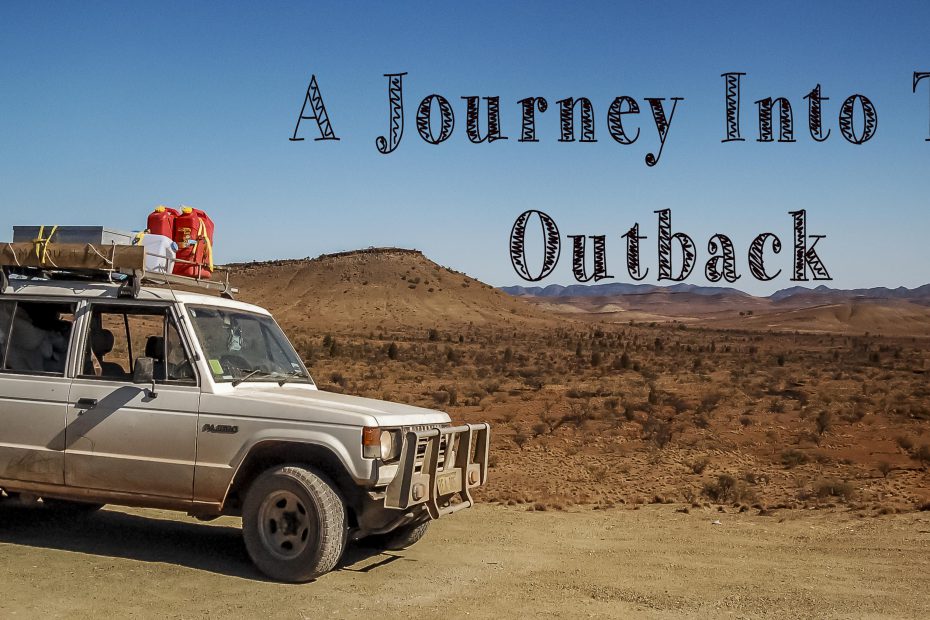 A four-wheel drive vehicle equipped for rugged travel, parked on an overlook with a vast arid landscape stretching into the distance, featured on a travel blog under the phrase "a journey into the outback
