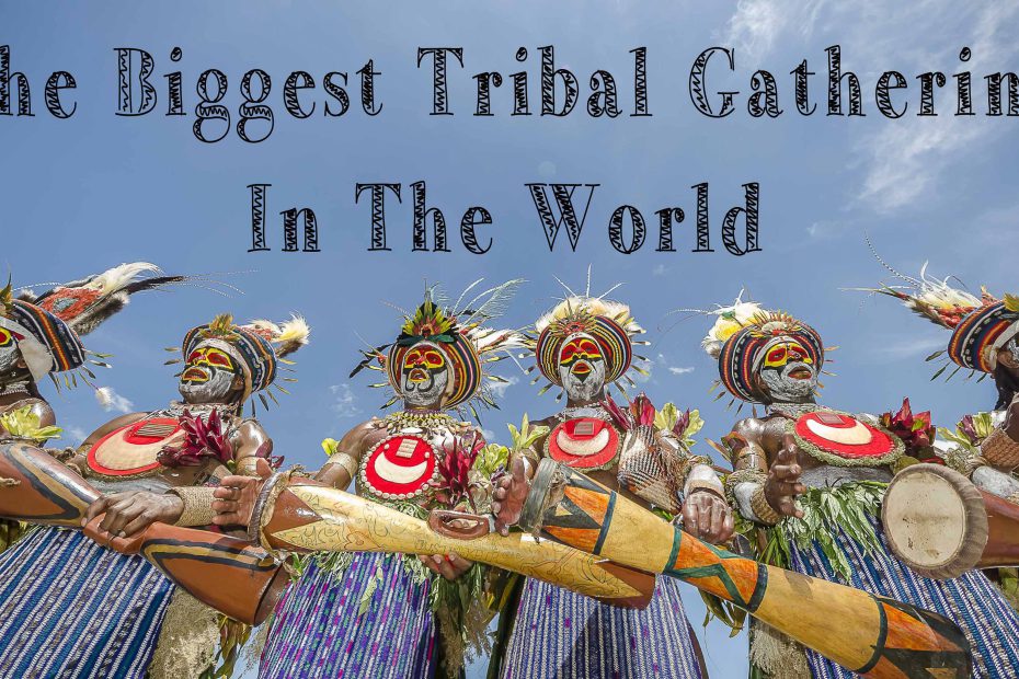 Indigenous people in traditional attire with painted faces and headdresses at a cultural festival featured on a travel blog.